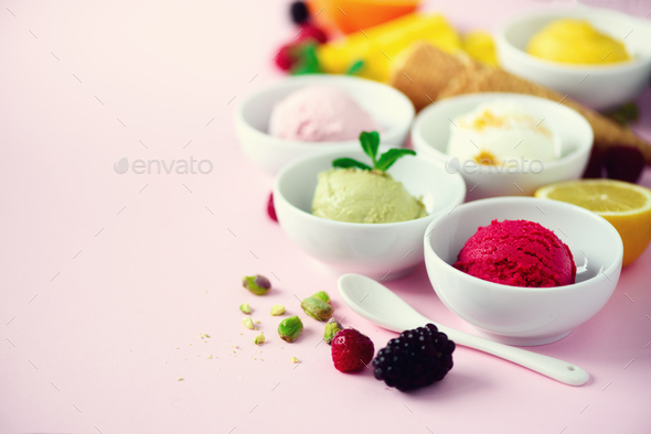 Red, purple, yellow, green, white ice cream balls in bowls, waffle cones, berries, orange, mango - Stock Photo - Images