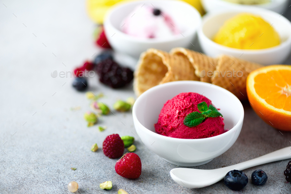 Top view red, pink, yellow, green, white ice cream balls in bowls, waffle cones, berries, orange - Stock Photo - Images