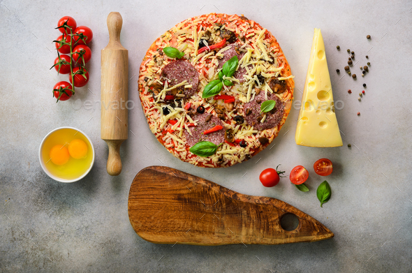 Food ingredients for italian pizza, cherry tomatoes, flour, cheese, basil, rolling pin, board, knife - Stock Photo - Images