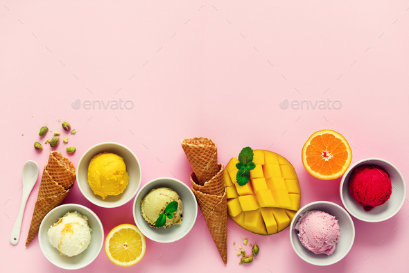 Top view red, purple, yellow, green, white ice cream balls in bowls, waffle cones, berries, orange - Stock Photo - Images