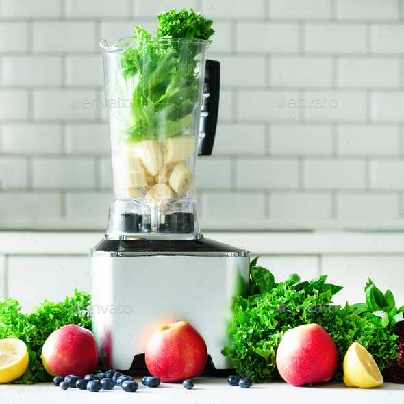 Woman blending lettuce leaves, spinach, aplles, berries, bananas. Homemade healthy green smoothie - Stock Photo - Images