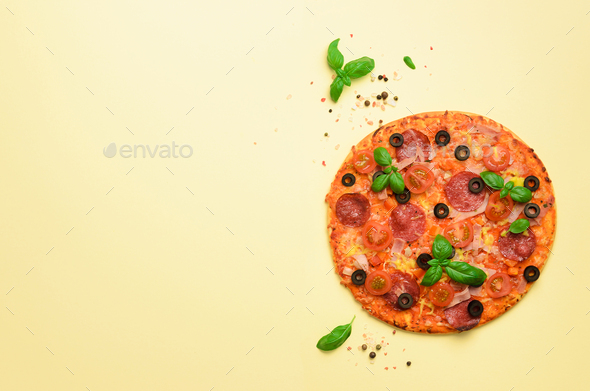 Delicious italian pizza, basil leaves, salt, pepper on yellow background with copyspace. Top view - Stock Photo - Images
