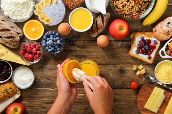 Woman squeezing orange fruit and making juice. Girl cooking breakfast. Healthy breakfast ingredients - Stock Photo - Images