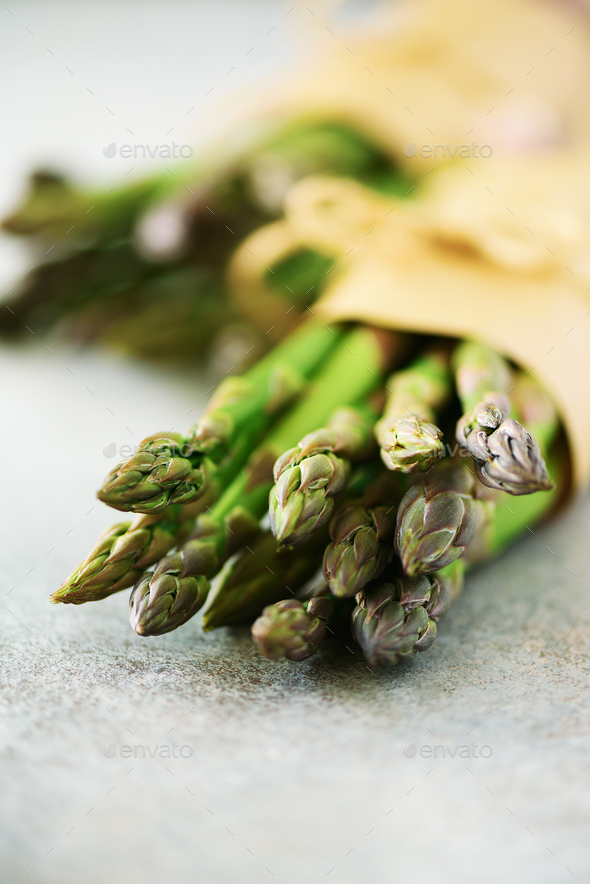 Bunch of fresh asparagus on gray backgrouns. Asparagus on craft paper with packthread. Raw, vegan - Stock Photo - Images