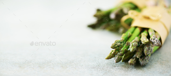 Fresh green asparagus in craft paper on marble background. Banner. Raw, vegan, vegetarian and clean - Stock Photo - Images