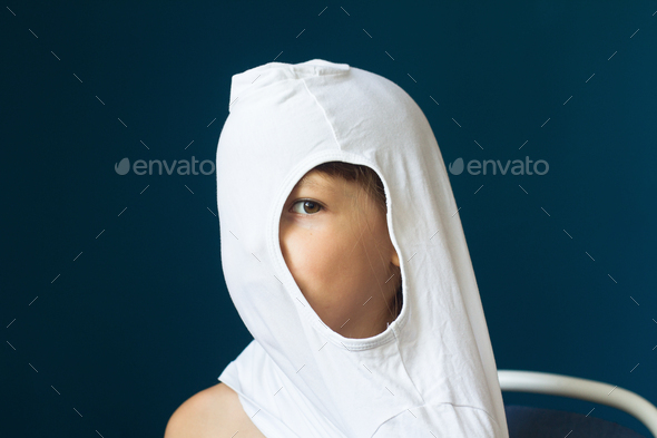 portrait of young child looking through the hole of his shirt - Stock Photo - Images