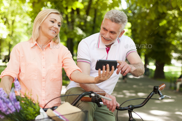 Happy mature couple with bike looking on mobile phone - Stock Photo - Images