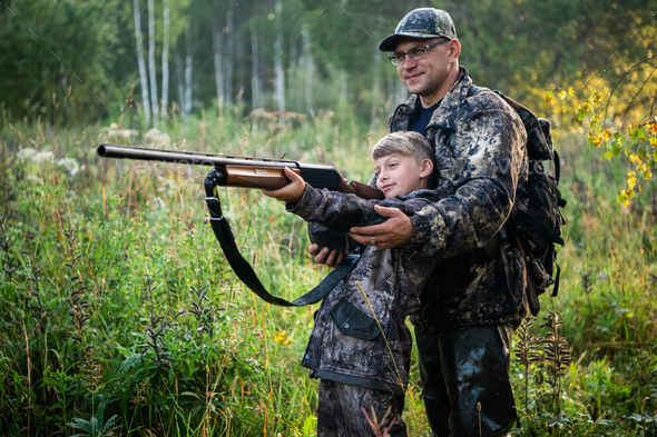 Father teaching his son about gun safety and proper use on hunting in nature