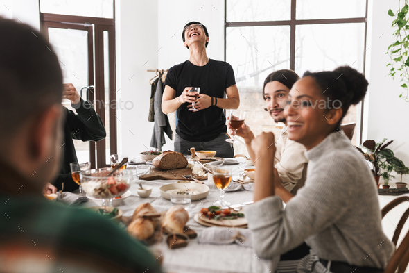Group of attractive international friends joyfully spending time together on lunch in cozy cafe - Stock Photo - Images