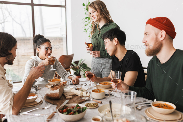 Pretty woman with wavy hair standing near table happily spending time with colleagues - Stock Photo - Images