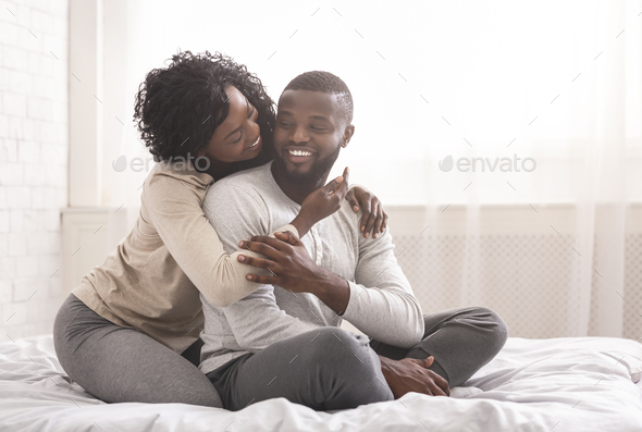 Romantic Millennial Couple Cuddling While Sitting In Bed In