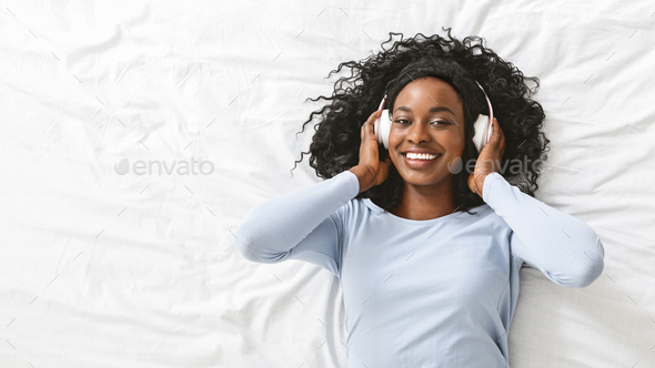 Excited woman listening to music in bed