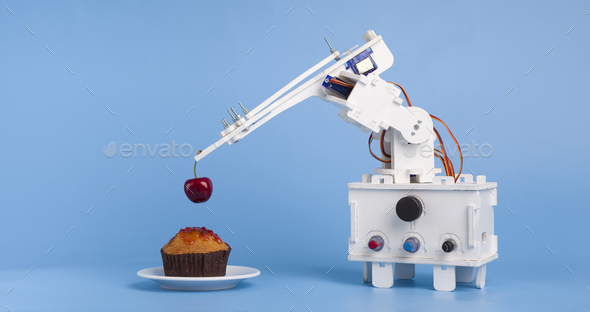 Robot cooking dessert, decorating sweet cupcake with fresh cherry