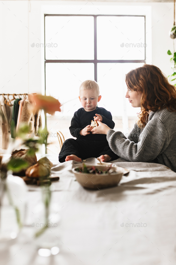 Young beautiful mom with red hair in knitted sweater dreamily playing with her little handsome son - Stock Photo - Images