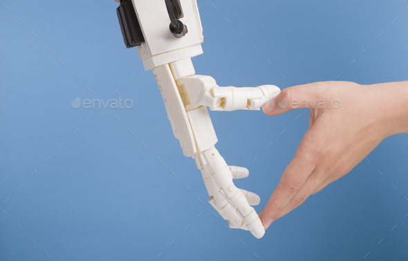 Human and robot hands making heart gesture on blue background