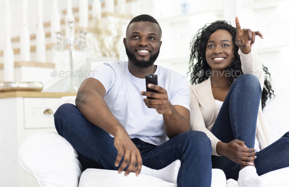 Black spouses watching tv together having fun at home