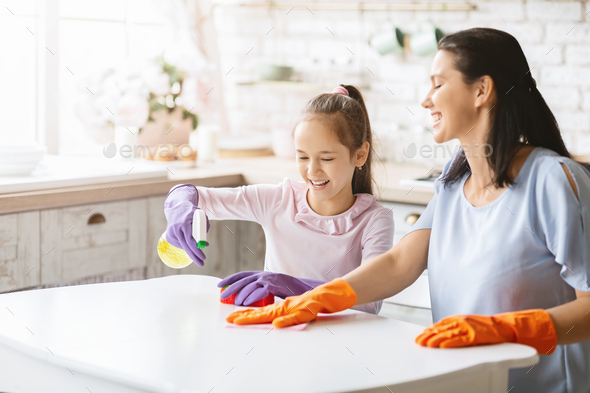 Cheerful mother and daughter cleaning kitchen together