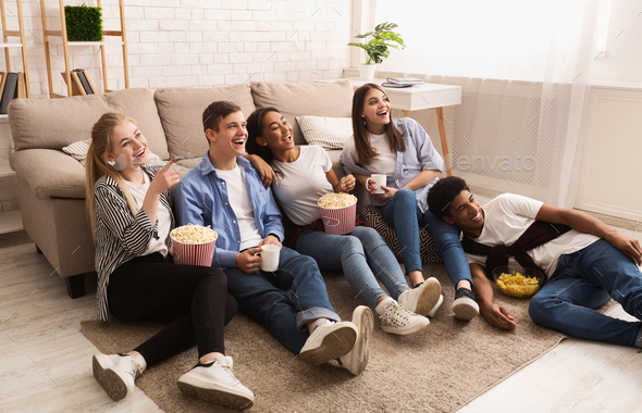 Happy friends watching comedy film and eating popcorn
