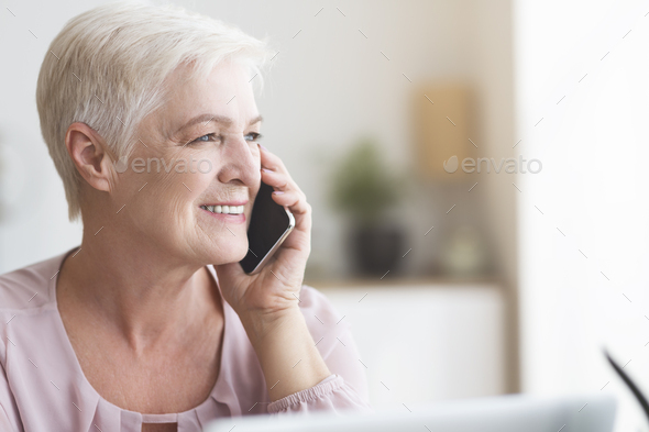Close up of mature business woman talking by phone - Stock Photo - Images