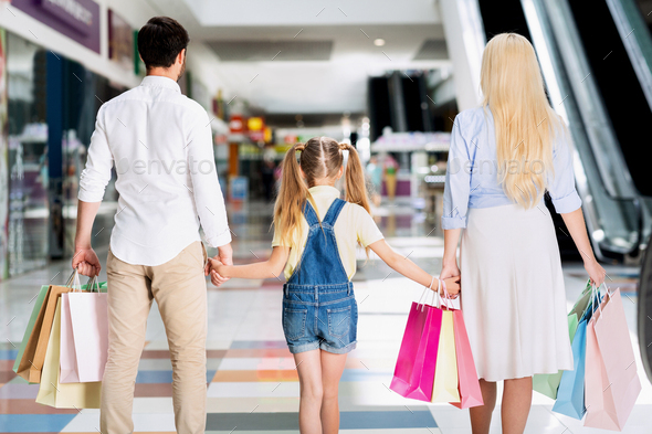 Unrecognizable Parents And Daughter Walking In Shopping Mall, Back View