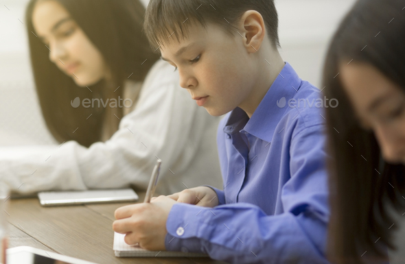 Pupils writing an exam test in classroom