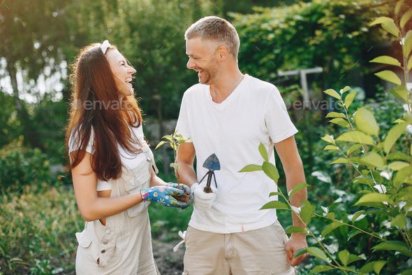 Beautiful couple works in a garden near the house