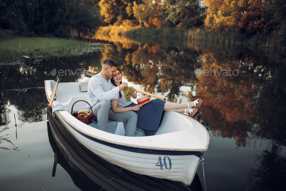 Love couple with fruit basket lying in a boat - Stock Photo - Images