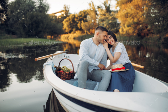 Love couple with fruit basket, relaxing in boat
