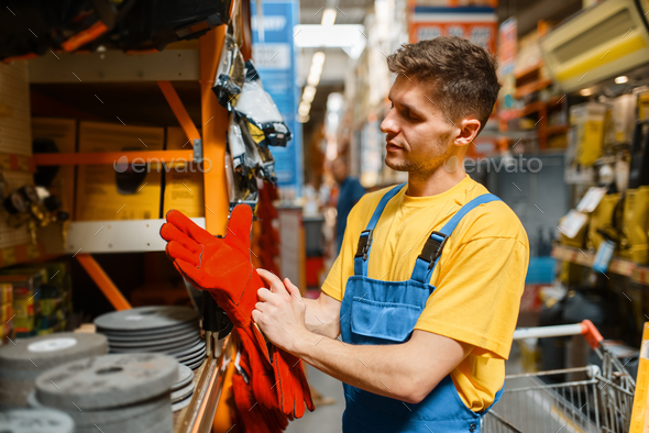 Male builder choosing gloves in hardware store