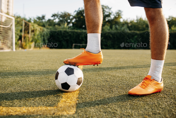 Male soccer player legs with ball standing on line