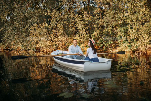 Love couple boating on lake, water reflection