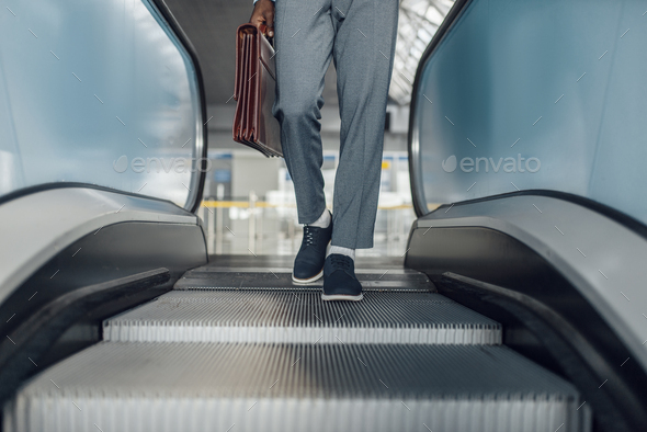 Black businessman descending on escalator in mall - Stock Photo - Images