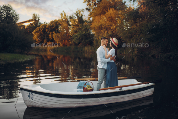 Lovers hugs in a boat on quiet lake at summer day