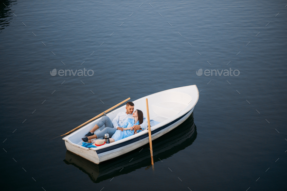 Love couple lying in a boat on lake, top view