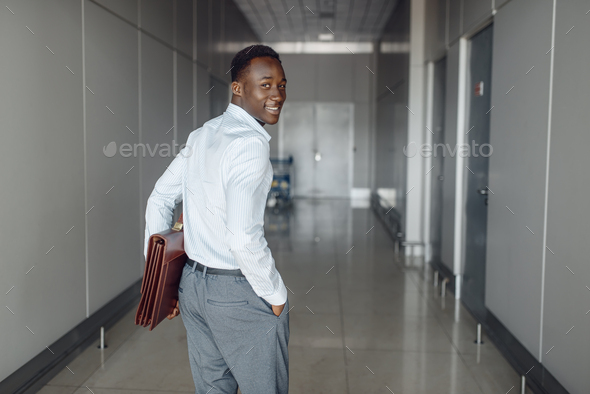Black businessman with briefcase in office hall - Stock Photo - Images