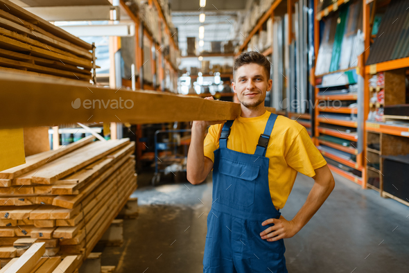 Male builder holds wooden boards in hardware store