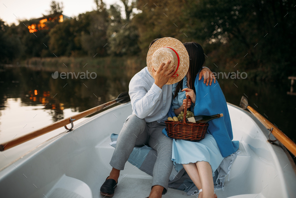 Love couple kissing in a boat on lake at sunset
