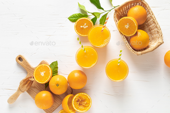 Orange juice. Freshly squeezed juice in glasses and fresh fruits with leaves, view from above