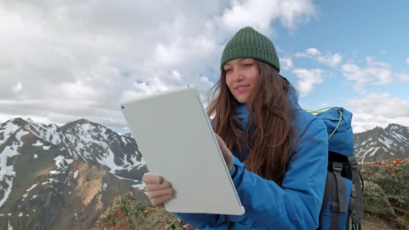 Girl Hiker with a Tablet Sitting on a Rock on a Background of Mountains and Lakes, Norway