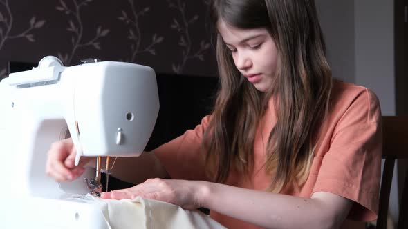 Little Girl Teenager Sews a Shopping Bag on a Sewing Machine alt
