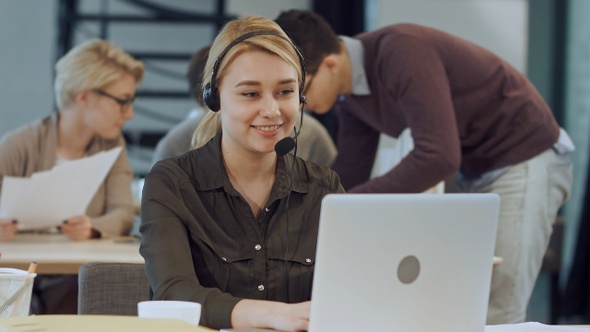 Smiling female helpline operator with headphones at her