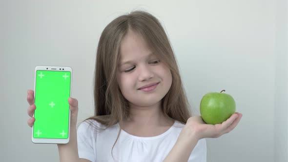 Little Girl Shows Apple and Phone with Green Screen Mock Up Cellphone Mobile Telephone alt