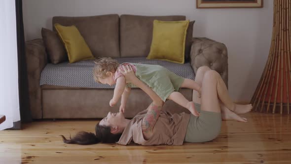 Happy Carefree Mother and Cute Small Child Daughter Tickling Laughing Having Fun Lying on Sofa and alt