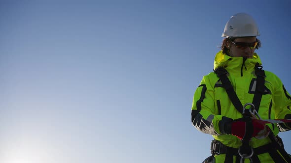 Industrial Climber Pulls Signal Tape on Roof of Building alt