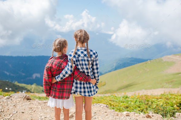 Beautiful happy little girls in mountains in the background of fog ...