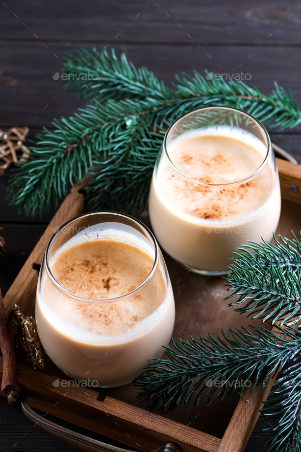 Eggnog Christmas milk cocktail with cinnamon, served in two glasses on vintage tray with fir branch - Stock Photo - Images