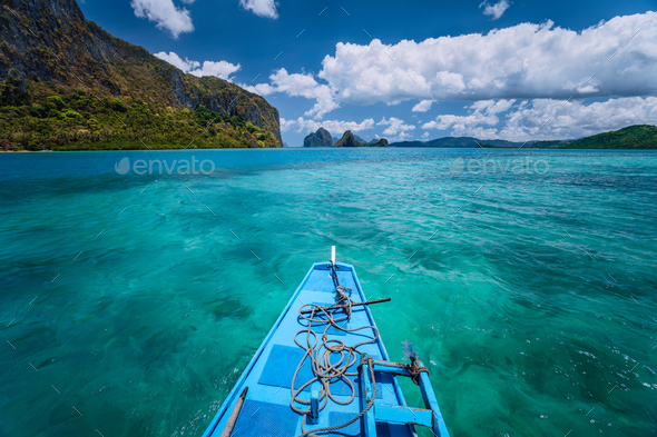 Island hopping Tour boat hover over open blue ocean water between exotic karst limestone islands on