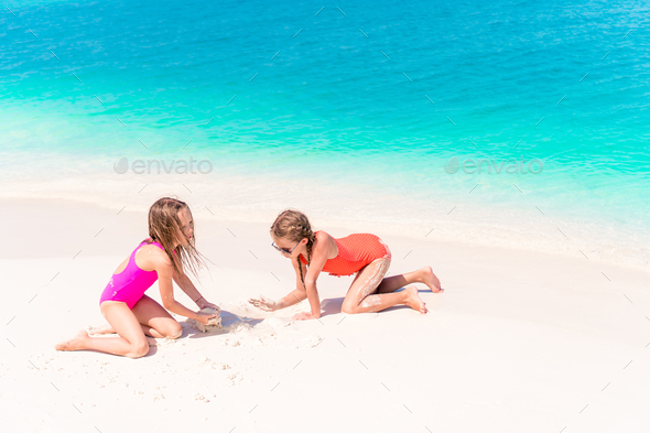 Two little happy girls have a lot of fun at tropical beach playing together - Stock Photo - Images