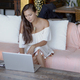 Beautiful brunette sitting on sofa and using laptop - PhotoDune Item for Sale