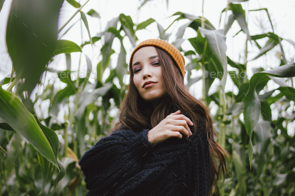 Beautiful carefree long hair asian girl in yellow hat and knitted sweater in autumn corn field - Stock Photo - Images